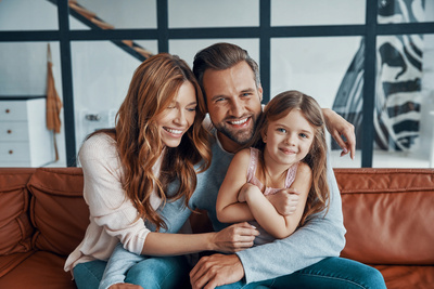 Eine glücklich lachende Familie mit Mutter, Vater und Tochter.
