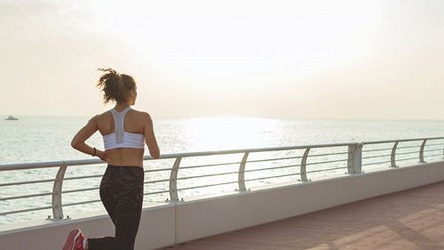 Eine Frau joggt am Meer entlang.