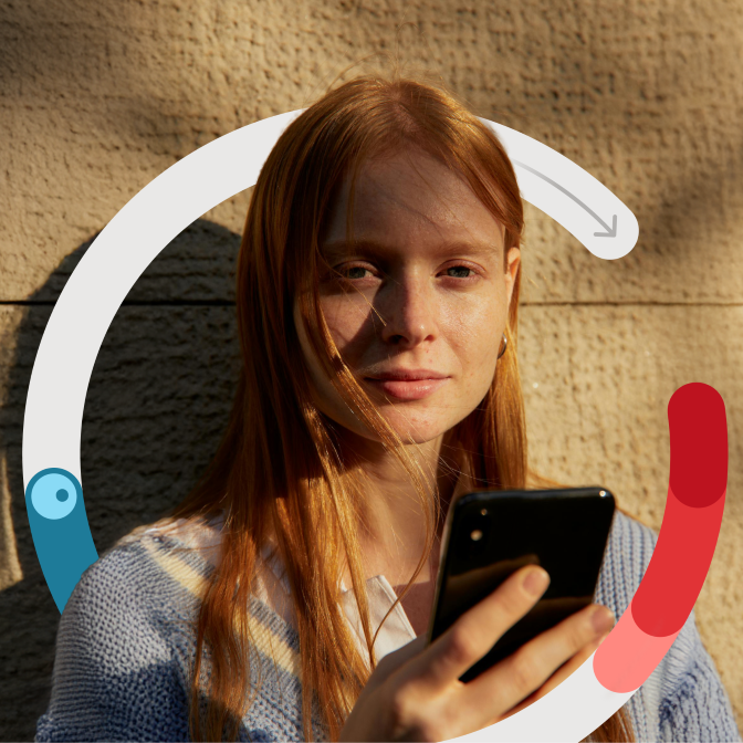 Frau hat ein Smartphone in der Hand und schaut in die Kamera.