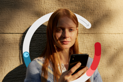 Frau hat ein Smartphone in der Hand und schaut in die Kamera.