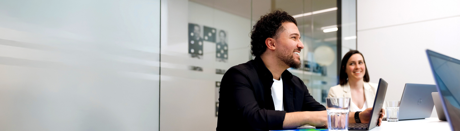 Zwei lächelnde Mitarbeiter der SDK sitzen vor ihren Laptops.