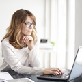 Eine Frau recherchiert konzentriert an ihrem persönlichen Laptop