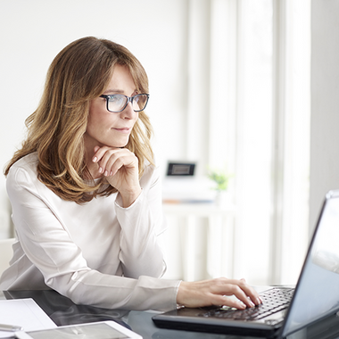 Eine Frau recherchiert konzentriert an ihrem persönlichen Laptop