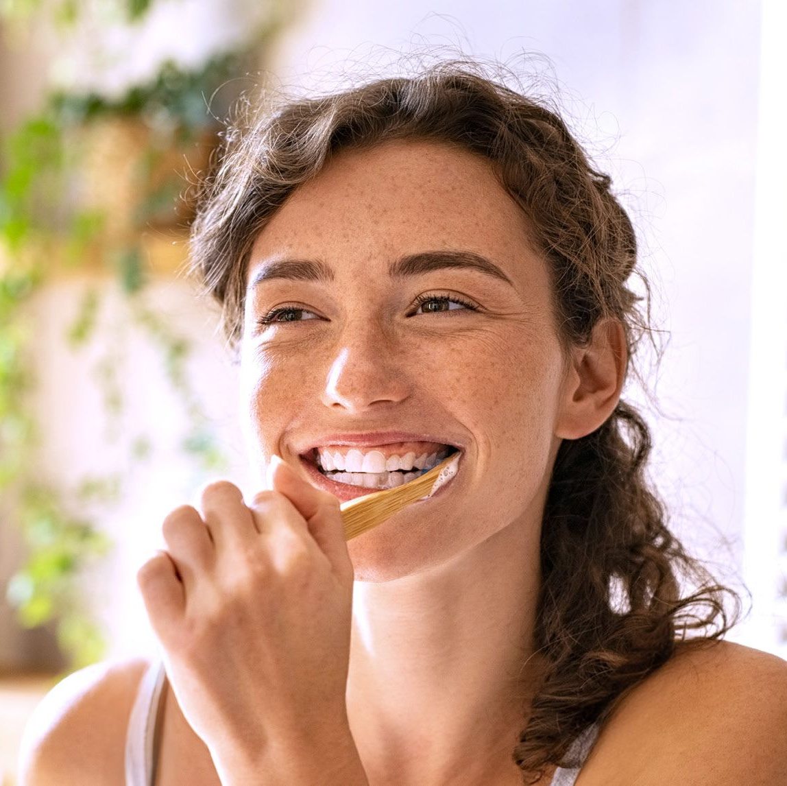 Frau putzt sich lächelnd die Zähne