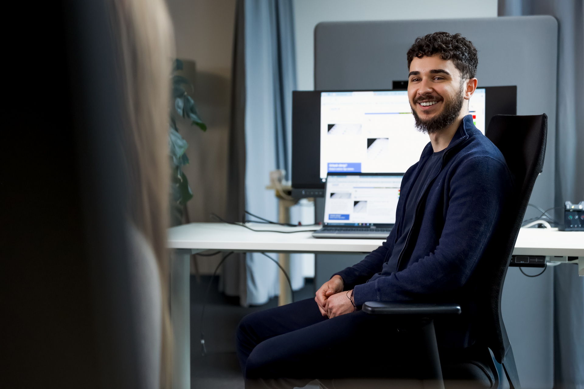 Ein lächelnder Auszubildender der SDK stizt vor einem PC in seinem Stuhl.