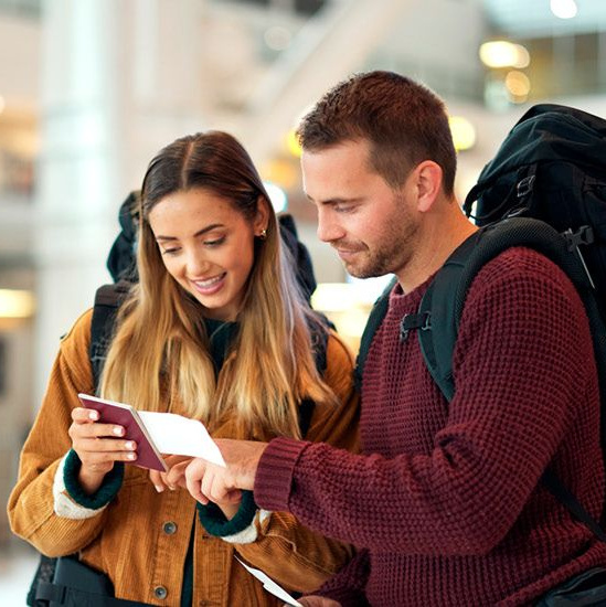Ein glückliches Paar am Flughafen schaut auf ein Reisedokument.