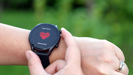 Eine Person bedient eine Smartwatch, die gerade den Puls der Person anzeigt.