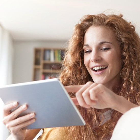 Eine lächelnde Frau bedient ein Tablet.