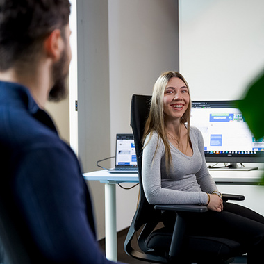 Zwei SDK-Mitarbeiter sitzen lächelnd im Büro.