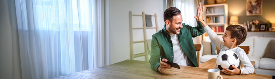 Vater klatscht sich mit seinem Sohn, der einen Fußball hält, ab.