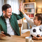 Vater klatscht sich mit seinem Sohn, der einen Fußball hält, ab.