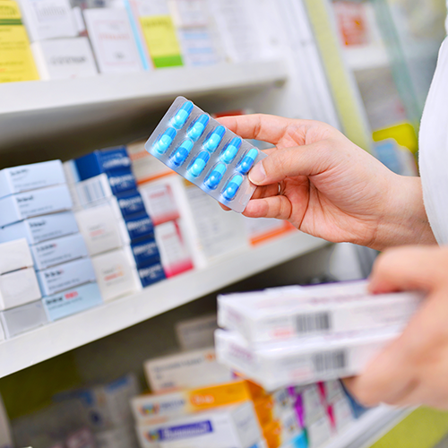 Eine Apothekerin betrachtet ein Blister mit blaufarbenen Medikamenten